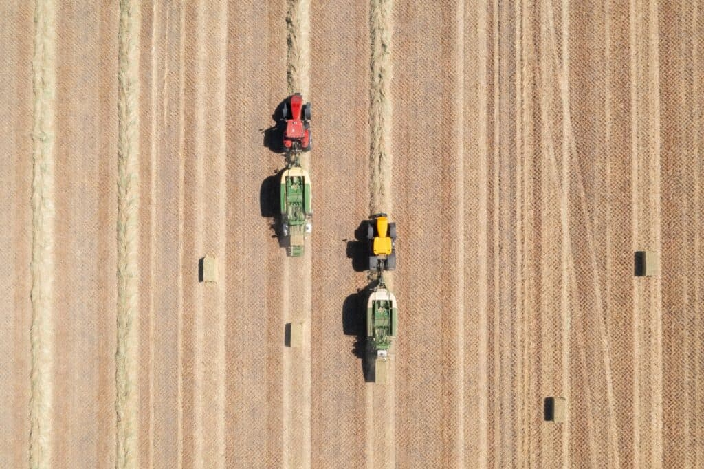 Machines bailing hay on farm